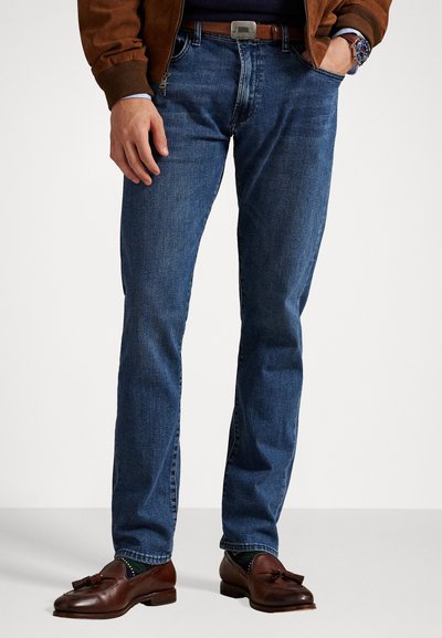 Blaue Jeans aus Denim mit geradem Schnitt, ausgestattet mit einem klassischen Fünf-Taschen-Design. Tragen mit braunen Lederschuhen und einem braunen Gürtel.