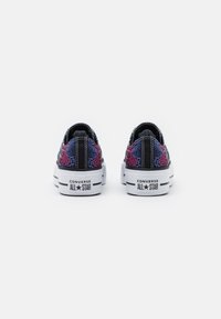 Zapatillas negras y multicolores con un patrón de piel de serpiente texturizada, suelas de goma blanca y la marca "CONVERSE ALL STAR" en el talón.