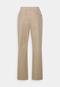 Beige broeken met een rechte snit, elastische tailleband, twee achterzakken met knopen en een subtiele logo-detail nabij de tailleband.
