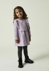 Lila långärmad klänning med blommönster, texturerad tyg, volangliv, parat med mörkgrå ribbade strumpbyxor och svarta snörkängor.
