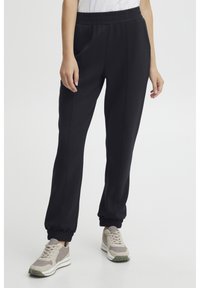SVART joggebukser med elastisk midjebånd, sidelommer og ribbestrikkede mansjetter. Laget av myk, lett stoff med en glatt tekstur.