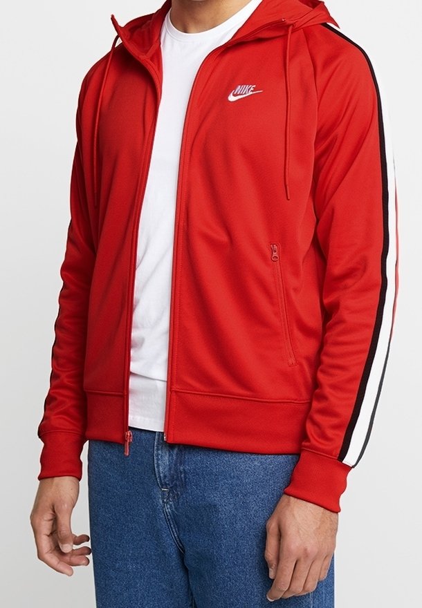 Veste de sport zippée rouge avec capuche, dotée de bandes latérales noires et blanches. Fabriquée en tissu lisse ; comprend une poche frontale et le logo Nike.