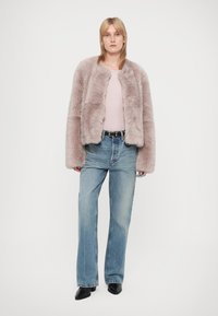 Ψεύτικο γούνινο cropped μπουφάν σε μαλακό ροζ, με χαλαρή εφαρμογή και φαρδιά μανίκια. Συνδυασμένο με ανοιχτό μπλε φαρδιές τζιν και μαύρες μυτερές γόβες.