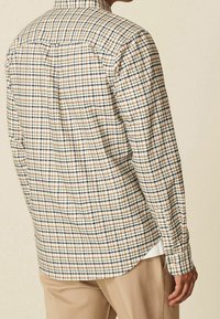Geruite shirt met een crèmekleurige basis, blauwe en bruine lijnen, lange mouwen, een button-down kraag en een afgeronde zoom.
