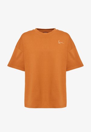 Oranžist puuvillast T-särk lõdva lõikega, lühikeste varrukate ja ümmarguse kaelusega. Esiküljel väike valge allkirjaga logo.