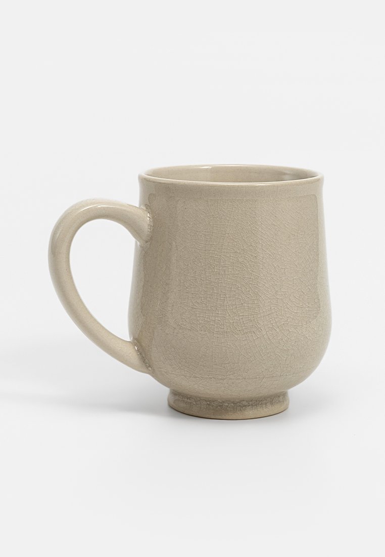 Beige Keramiktasse mit strukturierten Oberflächen, runder Form und stabilen Griff. Kurzer, stabiler Boden und glatter Rand.