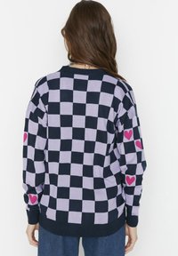 Sweter w marynarskim i lawendowym kolorze w kratkę, z długimi rękawami, z różowymi sercami na łokciach. Knitowany, luźny krój.