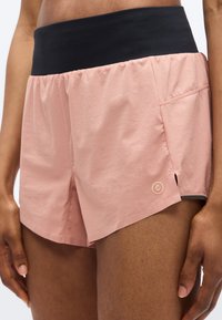 Ανοιχτό ροζ σορτς τρεξίματος με φαρδιά μαύρη μέση, πλαϊνές σχισμές και ένα μικρό λογότυπο στο κάτω δεξιά μέρος. Κατασκευασμένα από ελαφρύ, ελαστικό υλικό.