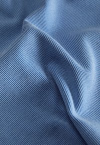 Tecido azul texturizado com riscas verticais estreitas, apresentando um acabamento suave. O material parece macio e ligeiramente amassado.