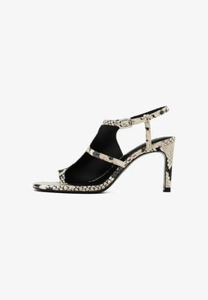 Högklackad sandal med ett svart och vitt ormskinnsmönster, öppen tå och en slingback-rem med en silverfärgad spänne som accent.