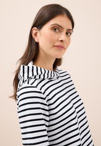 Sudadera a rayas en blanco y negro, hecha de una tela suave, presenta un cuello alto y un corte relajado con detalles de costura visibles.