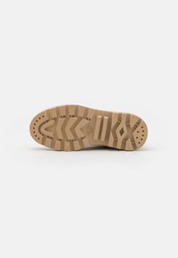 Semelle de chaussure marron clair dotée d'une semelle en caoutchouc texturé, avec des motifs en zigzag et des détails de traction circulaires. Logo de la marque.