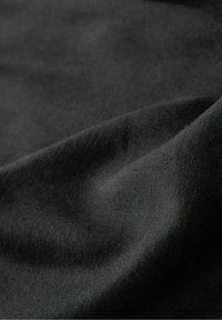 Černá látka s hladkým povrchem, mírně pomačkaná, s jemným, matným vzhledem. Materiál působí lehce a pružně.