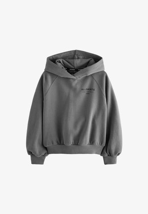 Jeune personne portant un sweat à capuche gris ample avec le texte « ALLSAINTS LONDON » et un pantalon cargo gris, posant devant un fond uni.