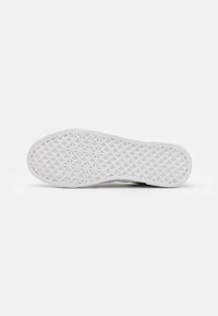 Semelle de chaussure en caoutchouc blanche avec un motif géométrique présentant des formes de diamant, offrant une adhérence texturée et une durabilité. Bords lisses avec une légère courbure.