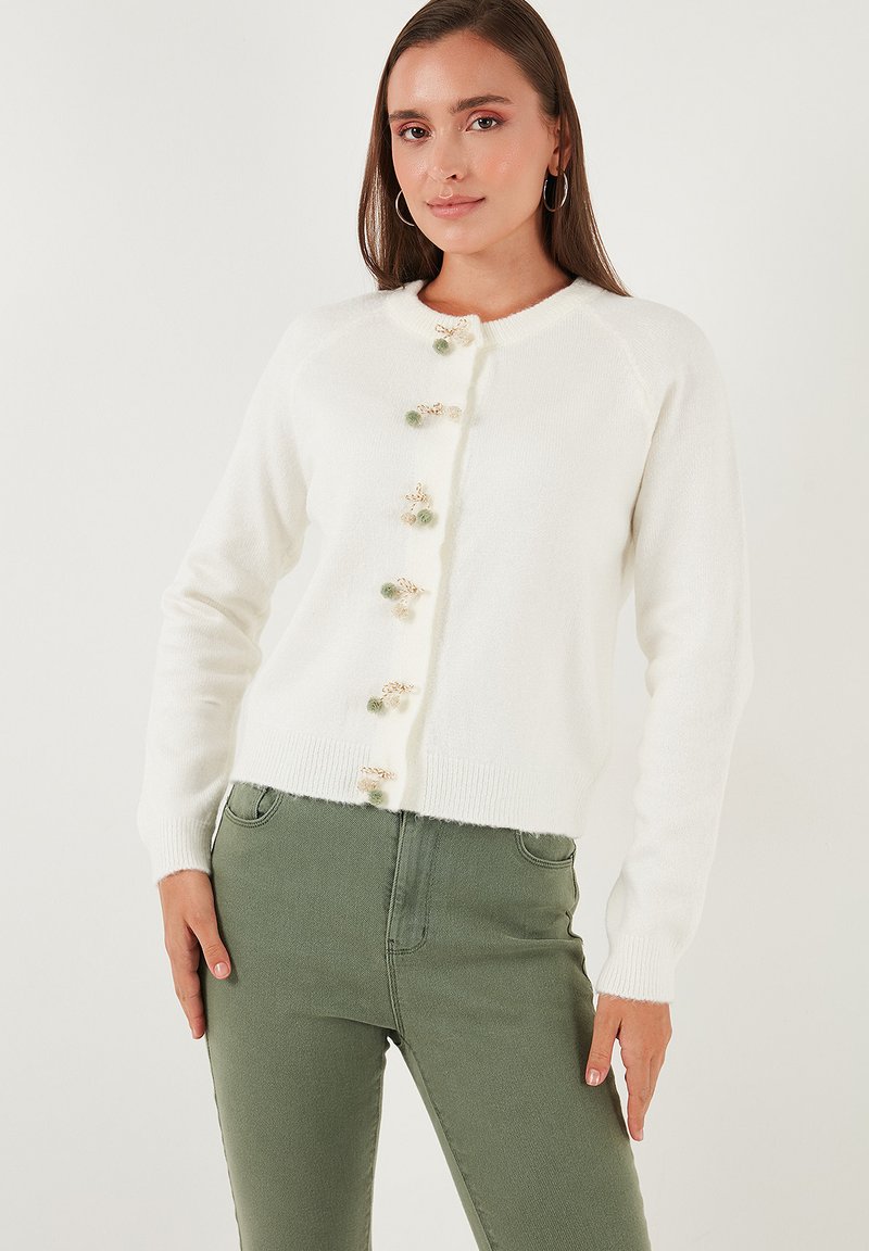 Cardigan blanco de mezcla de lana con cuello redondo, dobladillo acanalado y botones decorativos con pequeños acentos en verde y dorado. Mangas largas, estilo ajustado.