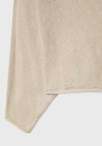 Beżowy sweter w dzianinę o luźnym kroju, z teksturowanym, miękkim materiałem i asymetrycznym dołem. Starannie wykonany z prążkowanymi krawędziami.