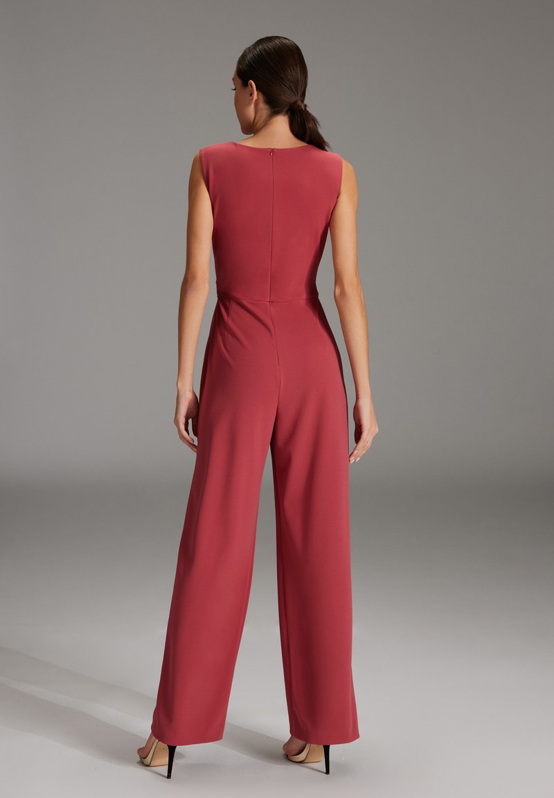 Czerwona, bezrękawna kombinezon z dopasowaną górą, szerokimi nogawkami i zamkiem błyskawicznym z tyłu. Gładka tkanina o matowym wykończeniu.