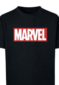 Černé bavlněné tričko s výrazným červeným obdélníkovým logem, na kterém je v tučných bílých písmenech napsáno "MARVEL" přes hruď.