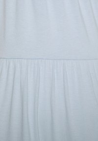 Hellblauem Stoff mit horizontaler Naht und darunter gerafften Falten, die Textur und Nahtdetails zeigen.