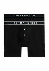 Caleçon nero con una waistband di logo Tommy Hilfiger, chiusura frontale con bottone e una texture di tessuto morbido e liscio.