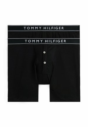 Caleçon nero con una waistband di logo Tommy Hilfiger, chiusura frontale con bottone e una texture di tessuto morbido e liscio.
