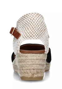 Sandaletta con zeppa in suede nero, con retro intrecciato bianco e beige, caratterizzata da un accento in cuoio marrone e una suola in juta.