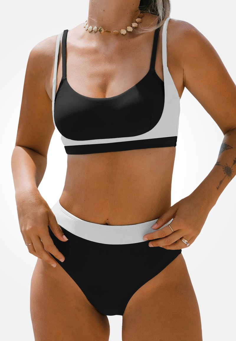 Schwarzes und weißes Bikini-Set mit einem enganliegenden Oberteil mit dünnen Trägern und hochtaillierten Bottoms. Glattes, dehnbares Material mit minimalen Details.