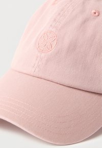 Ροζ ανοιχτόχρωμο καπέλο του μπέιζμπολ με κυρτό γείσο και κεντημένο έμβλημα λουλουδιού στην μπροστινή πλευρά, εμφανιζόμενο σε λευκό φόντο.