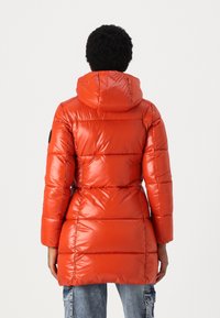 Rode pufferjack met capuchon, met een glanzende afwerking, geborduurd patroon en zwarte accenten op de mouwen. Middenlange ontwerp.