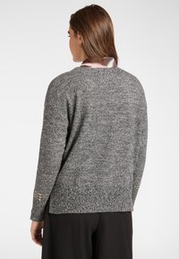 Grauer Pullover mit strukturiertem Strickdesign, langen Ärmeln und dekorativen goldenen Akzenten an den Bündchen. Verfügt über eine lockere Passform und einen abgerundeten Saum.