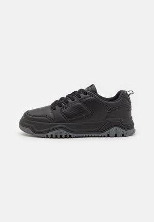Czarny niskoprofilowy sneaker z teksturowaną podeszwą, sznurowaniem z przodu, wyściełanym kołnierzem i perforowanymi panelami w widoku bocznym na białym tle.