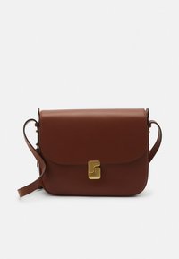 Bolso de cuero marrón para llevar al hombro con cierre de solapa, detalle metálico dorado en el frente y una correa ajustable. Textura suave y forma rectangular.