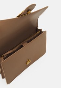Brown leather handbag with a flap closure, a gold button accent, and a zippered compartment inside. Features sleek, minimalist design.