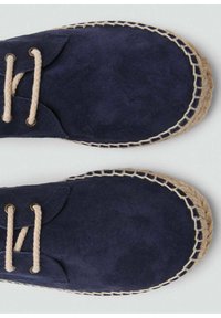 Espadrillas in suede blu navy con lacci beige, caratterizzate da una suola in juta intrecciata e dettagli cuciti lungo il bordo. Texture liscia.