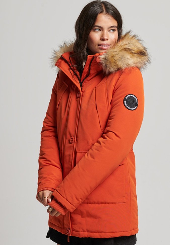Vrouwen oranje geïsoleerde parka met een afneembare nepbontcapuchon, drukknoopsluiting, ritszakken en ribgebreide manchetten voor warmte.