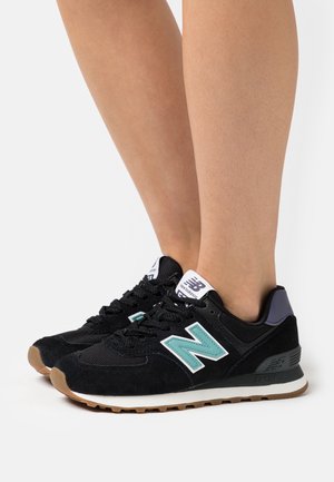 Black suede and mesh sneakers with mint green "N" logo, rubber sole, and black laces. Features a padded collar and white accents.