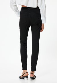 Jeans skinny negros con una cintura alta, que cuentan con dos bolsillos traseros y una tela suave y elástica. Combinados con tacones negros con tiras.