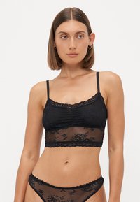 Sort blonde bralette med gennemskinneligt mesh-stof, justerbare stropper og en scalloped blondekant. Inkluderer detaljer med blomster mønster.