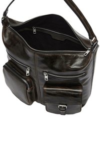 Brązowa skórzana torebka na ramię z wieloma zamykanymi na zamek kieszeniami, gładką fakturą i szerokim paskiem. Wnętrze wyściełane ciemną tkaniną.