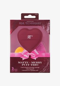Set Real Techniques Matte + Merry Puff Trio in un contenitore rosso a forma di cuore; include una mini spugna gialla, un puff sfumante rosa e un puff per cipria.