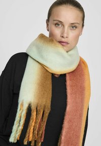 Écharpe en laine présentant un dégradé de couleurs allant du crème à l'orange et au marron, avec des extrémités à franges et une finition douce et texturée.