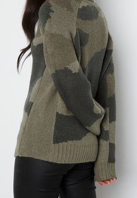 Maglione camouflage verde oliva con una morbida trama a maglia, orlo a coste e maniche lunghe con una silhouette rilassata.