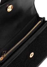 Portafoglio in pelle nera con un accento in tessuto nero testurizzato, caratterizzato da una zip dorata e una chiusura a scatto. L'interno presenta diversi scomparti.