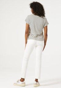 Top de manga corta a rayas en beige y negro, combinado con jeans rectos blancos y zapatillas gris y blancas. Tejido texturizado, corte relajado.