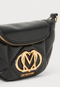 Schwarze Schultertasche aus Kunstleder mit gestepptem Muster, goldfarbener Hardware und auffälligem "Love Moschino"-Logo auf der Vorderseite. Mit Reißverschluss.