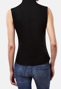 Sort ærmeløs top med høj hals, der har en tætsiddende silhuet og glat tekstur. Kombinationen med blå denim jeans.