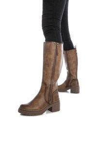 Botas marrones hasta la rodilla con un acabado de cuero sintético suave, un cierre lateral de cremallera y un tacón bloque grueso. Suela texturizada para mayor tracción.