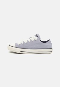 Light gray suede sneaker with white laces, rubber toe cap, and black stripe detail. Design features low-top silhouette and padded tongue.