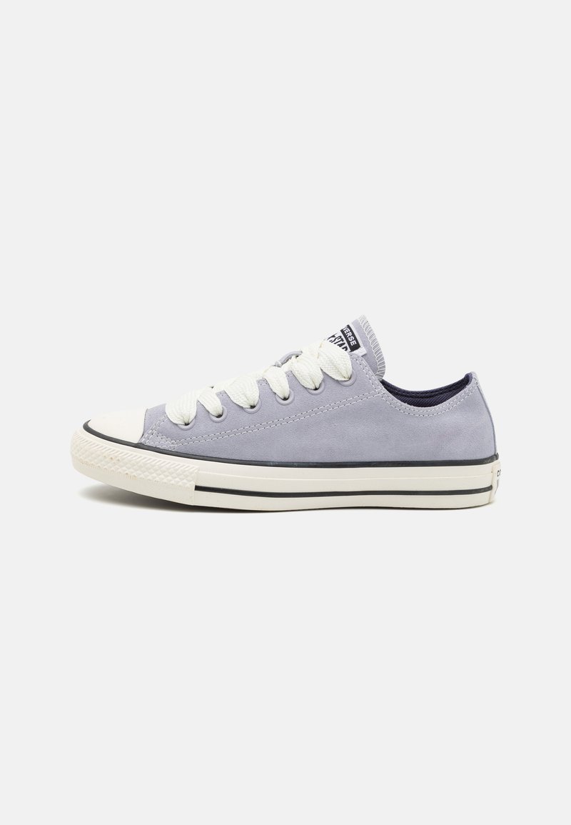 Light gray suede sneaker with white laces, rubber toe cap, and black stripe detail. Design features low-top silhouette and padded tongue.